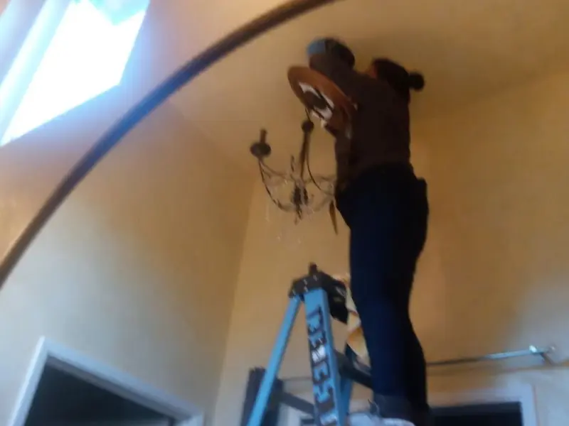 Electrician installing a chandelier in a Haddon residence